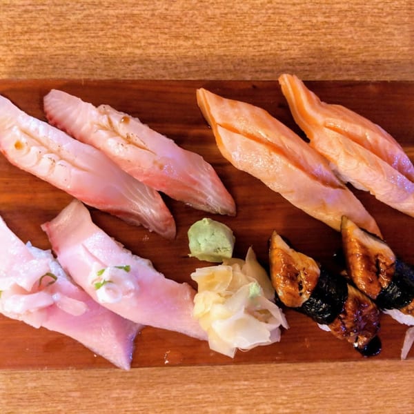 Assortment of Koryo Sushi nigiri, including salmon, white fish, and eel, with ginger and wasabi.