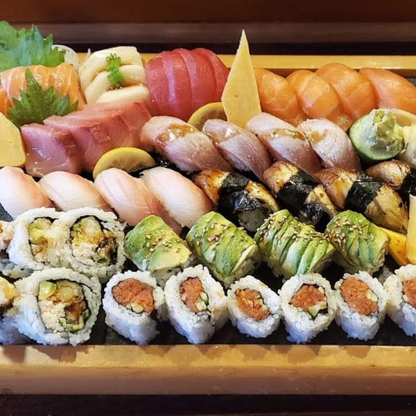 A large Koryo Sushi platter with various nigiri, sashimi, and sushi rolls arranged on a wooden tray.