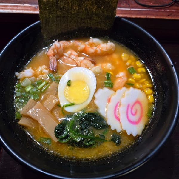 Koryo Sushi ramen bowl with shrimp, egg, fish cake, corn, and greens in broth.