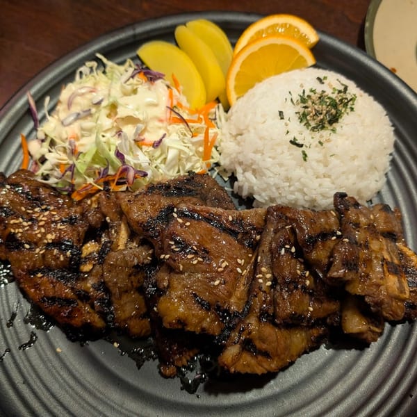 Grilled short ribs with sesame seeds, white rice, coleslaw, orange slices, and pickled daikon.